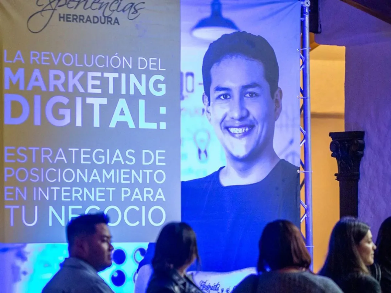 Público frente al banner de la conferencia de Josué Moya de la Cruz «La revolución del marketing digital: estrategias de posicionamiento en internet para tu negocio»